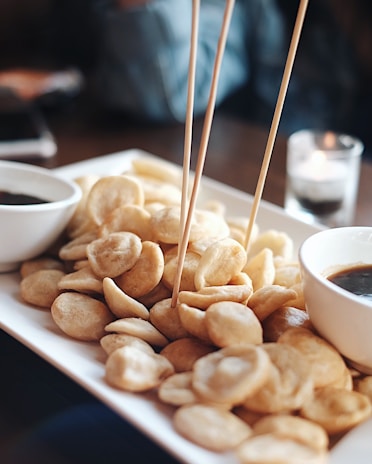 Close-up of a crispy golden snack platter with dipping sauces on a rustic wooden table.