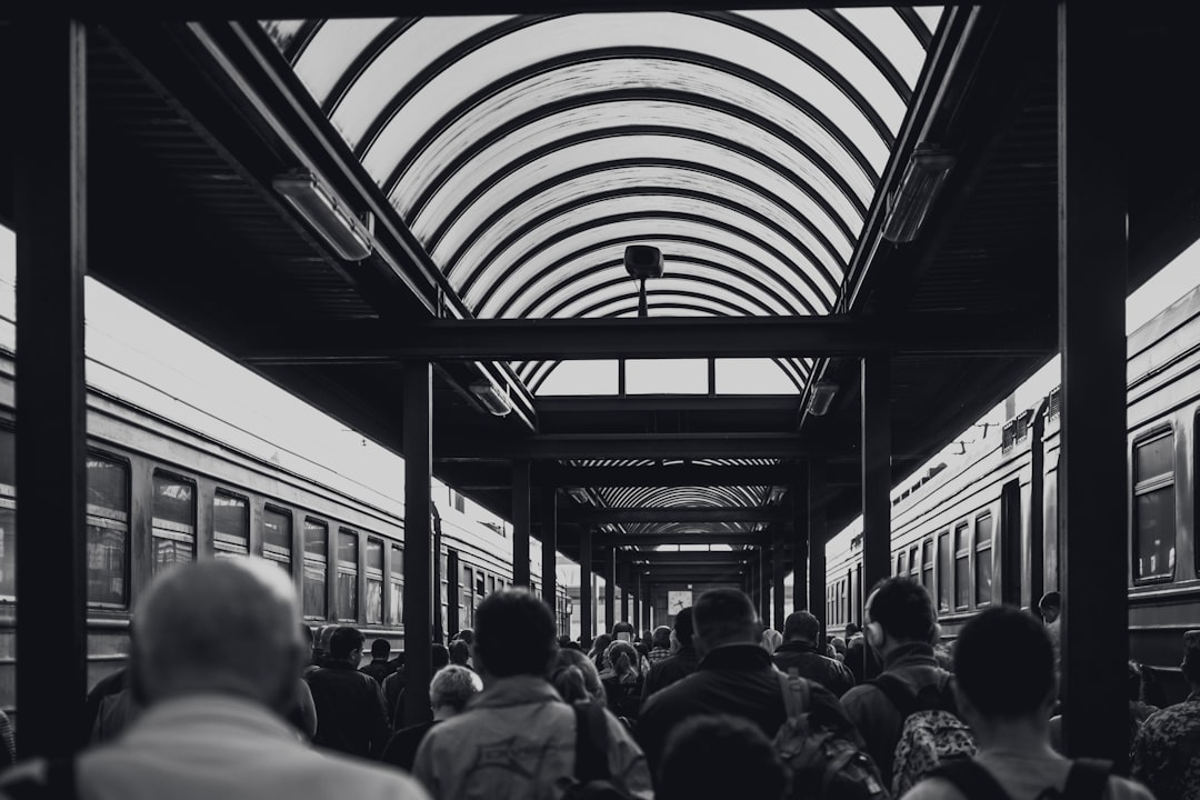 grayscale photo of people under waiting shed,