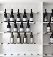 Elegant wine bottles displayed on a minimalist white shelf, highlighting their labels.