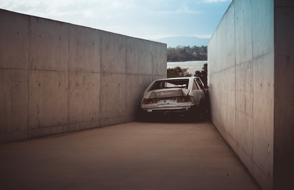 wrecked gray vehicle between concrete walls at daytime