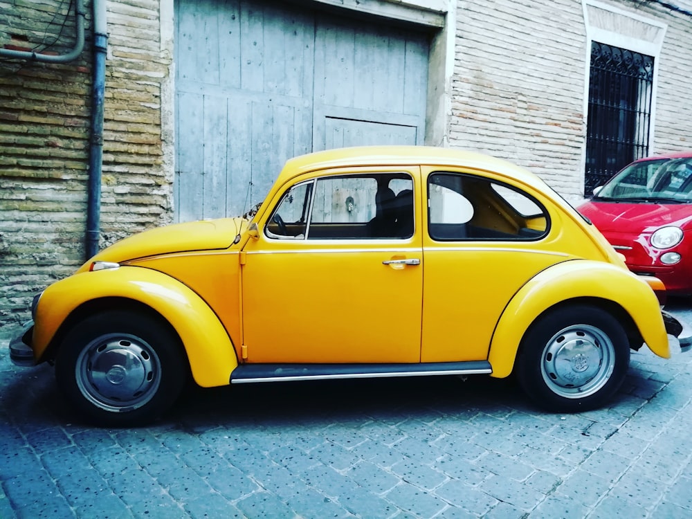 yellow Volkswagen beetle parked near building