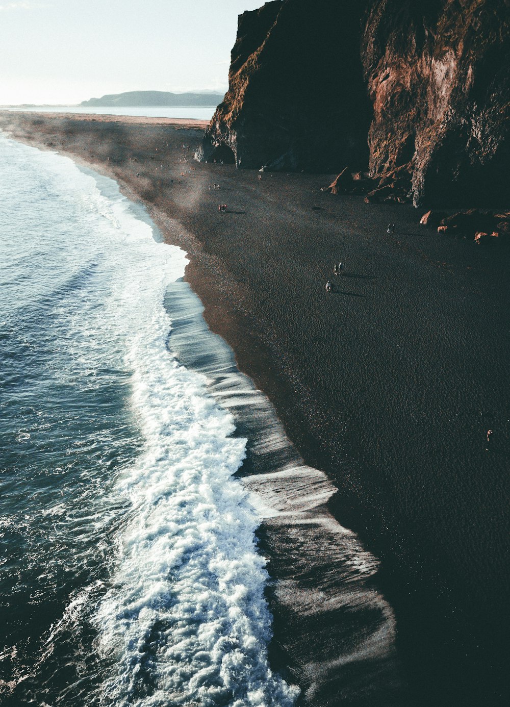 a black beach with waves coming in to the shore