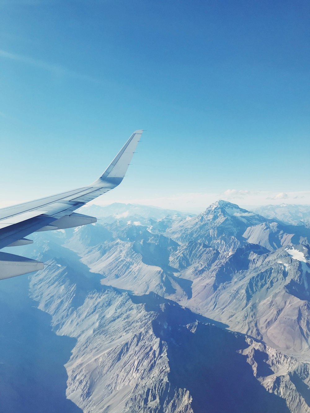 An airplane window with a view of the snow covered mountains photo – Fly  Image on Unsplash