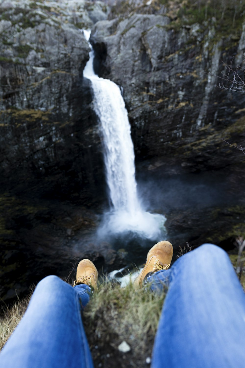 person sitting on cliff near water falls