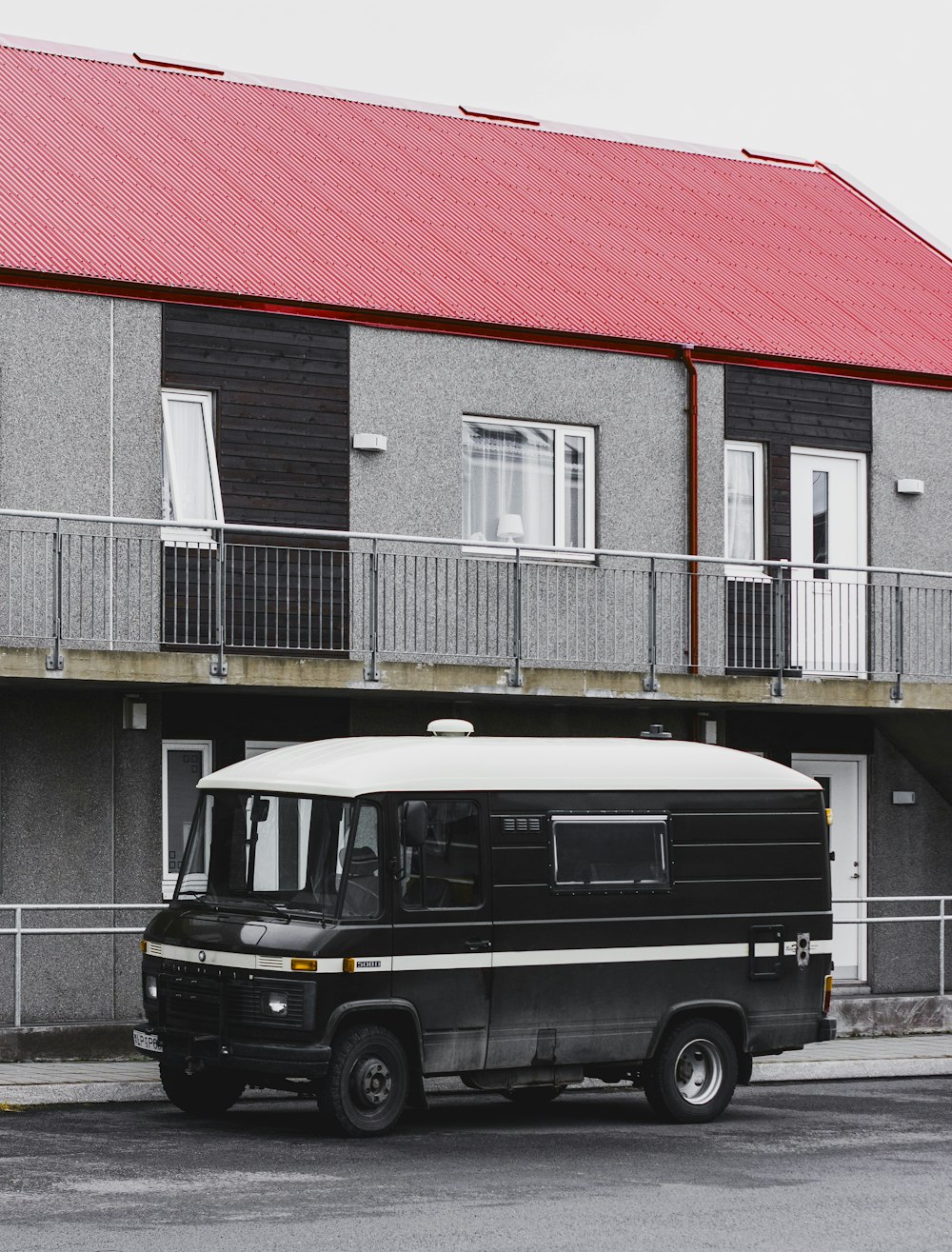 black vehicle parked in front of grey 2-storey house
