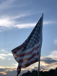 An American flag gently waving behind a professional office building at sunset.