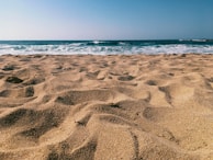 View of the nearby Jomtien Beach with golden sand and calm waves under a clear sky.