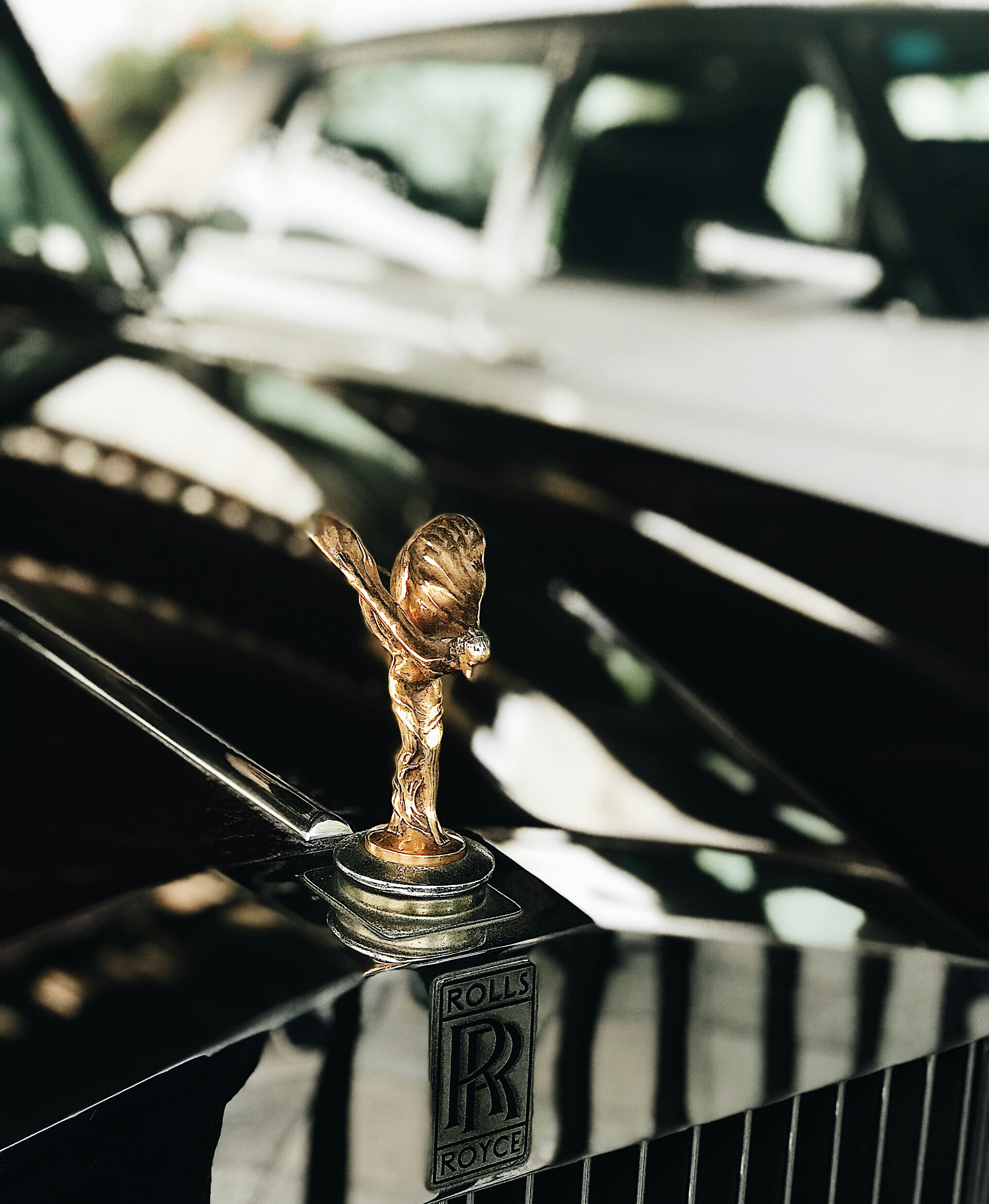 Rolls-Royce Phantom in Obsidian Black, dramatic night lighting, long wheelbase silhouette with Spirit of Ecstasy gleaming on hood