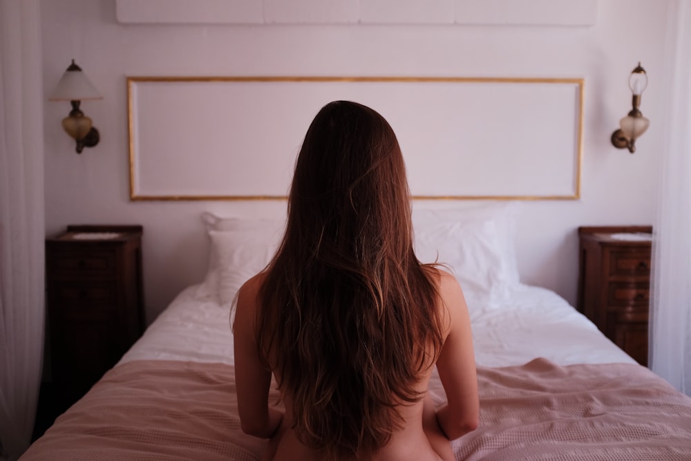 ベッドに座っているトップレスの女性