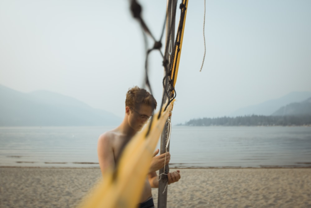 standing man beside net on beach during daytime