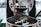 Close-up of a coffee roasting machine in action, with freshly roasted coffee beans pouring out into a metal tray. The machine has various metal components, knobs, and parts that help in the roasting process.