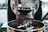 Close-up of a coffee roasting machine in action, with freshly roasted coffee beans pouring out into a metal tray. The machine has various metal components, knobs, and parts that help in the roasting process.