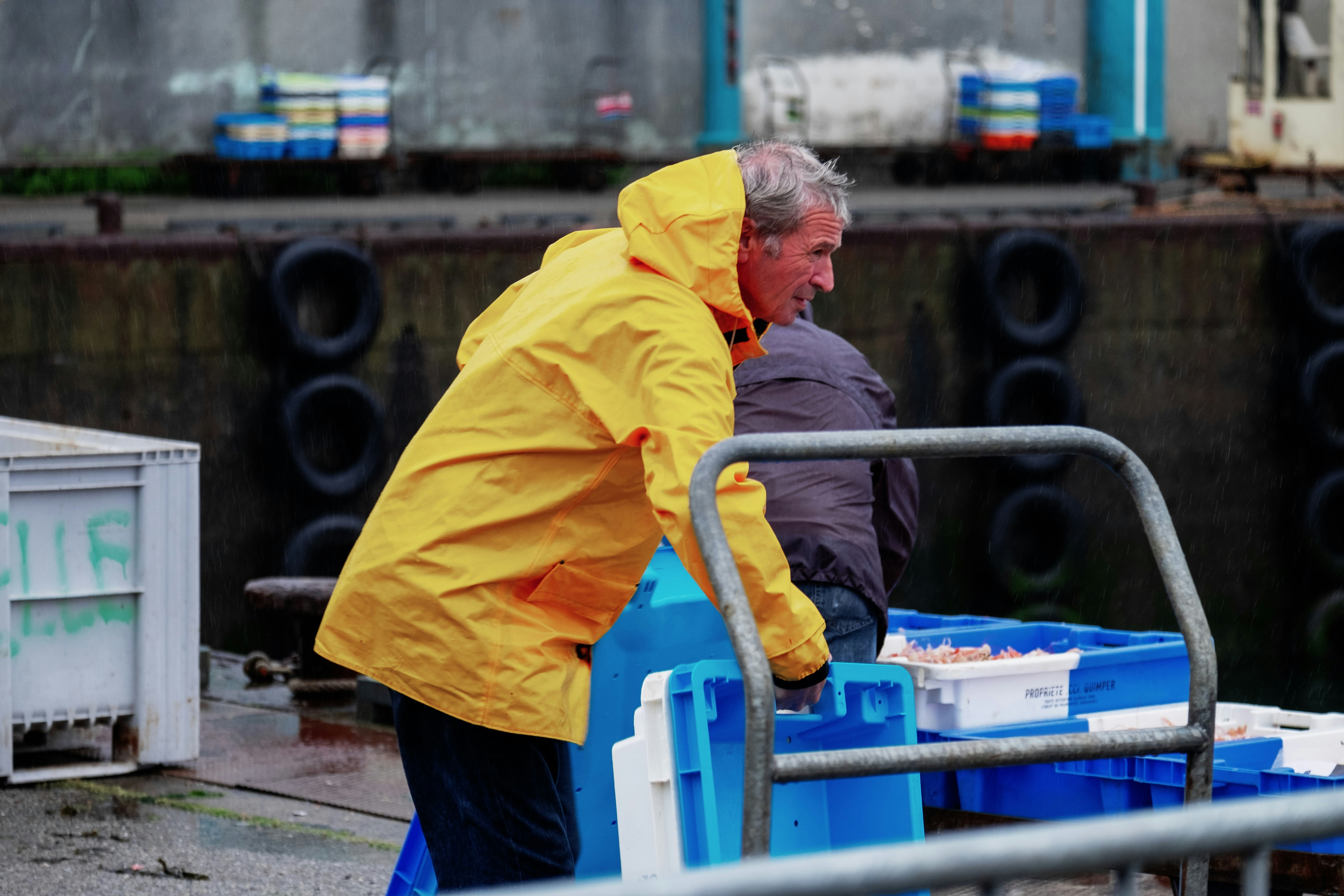man standing while picking up blue and white plastic crates