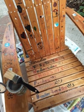 A painter applying glossy enamel paint on a wooden office chair.