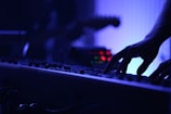 A person playing piano keys under moody blue lighting.