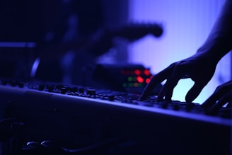 A close-up of a composer’s hands playing piano keys in a dimly lit studio.