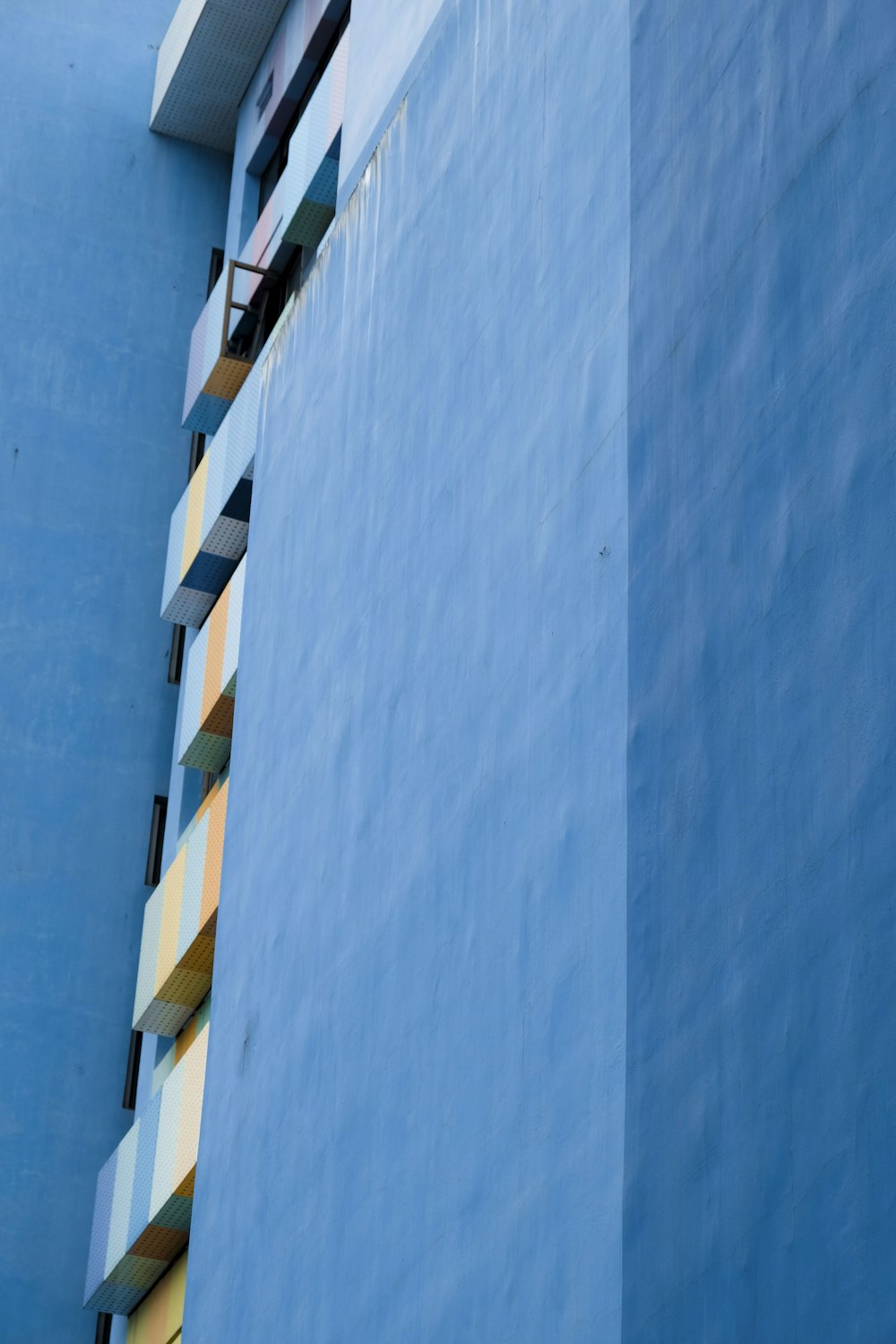 Un edificio azul alto con un reloj en su lado