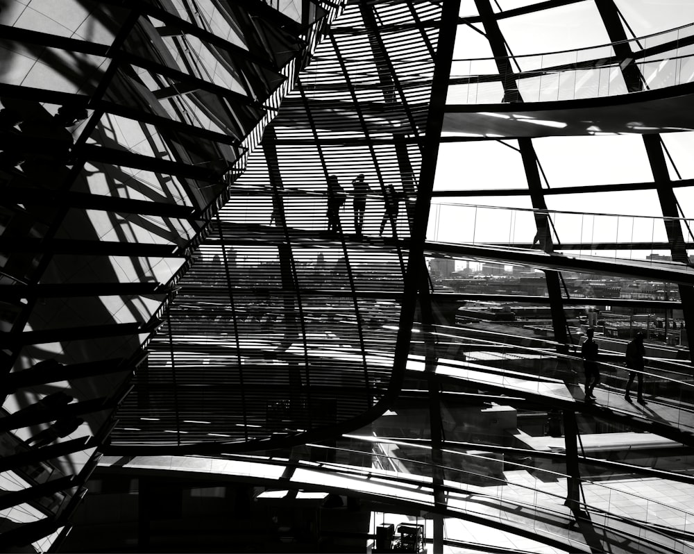 grayscale photography of three people standing inside metal building