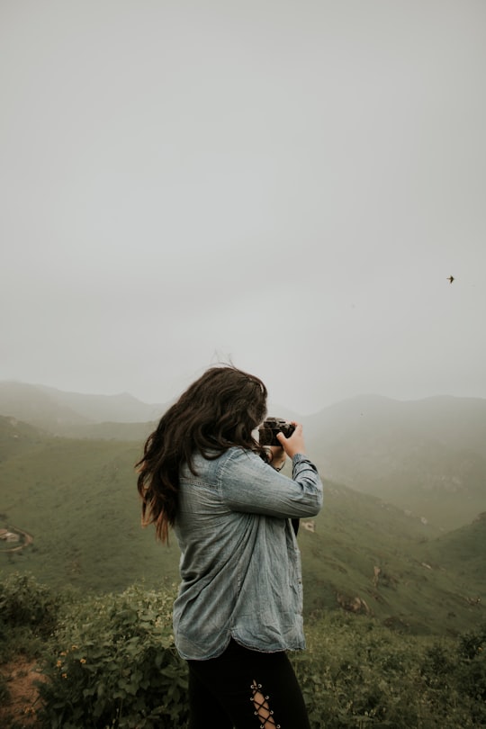 woman taking photo of mountain during daytime in Lomas de Lachay Peru