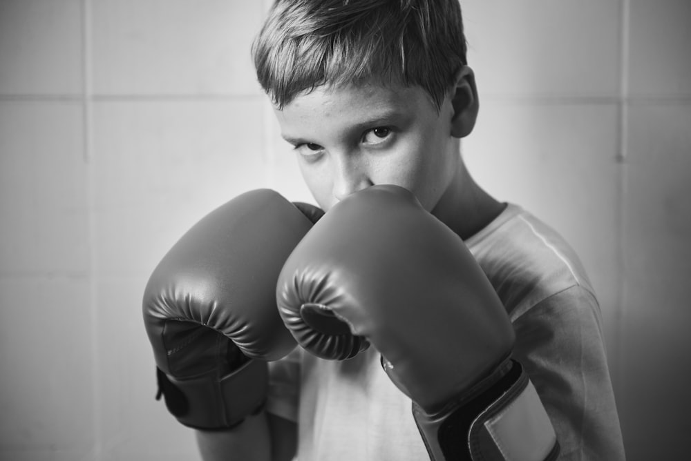 grayscale photo of boy wearing boxing gloves