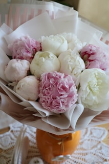 A custom bouquet of pale pink peonies and cream ranunculus tied with a silk ribbon