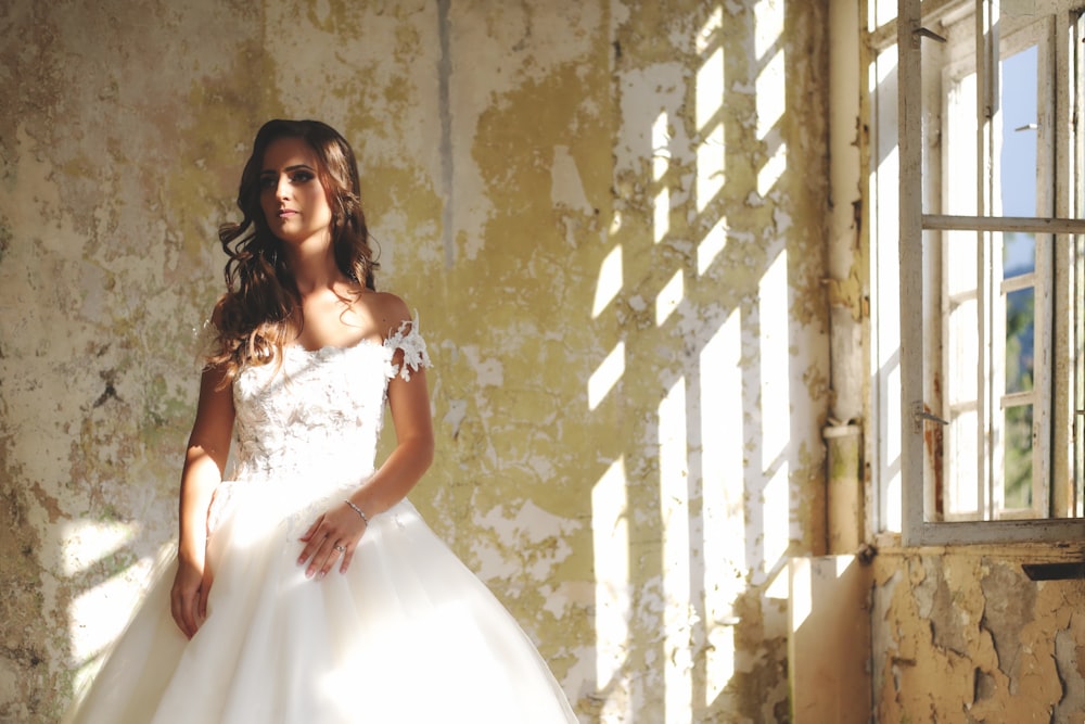 woman in bridal gown standing near window