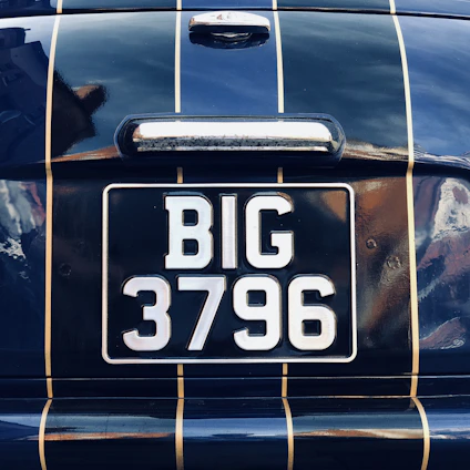 Close-up of vintage and modern vehicle identification plates displayed on a sleek black surface.
