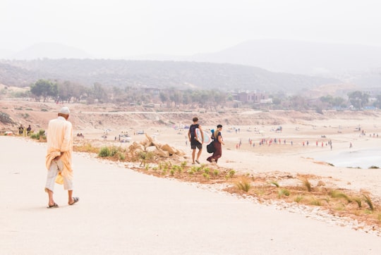 man wearing brown coat walking on brown road in Taghazout Morocco