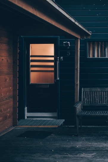 A cozy front porch featuring a beautifully crafted wooden door bathed in warm sunlight.