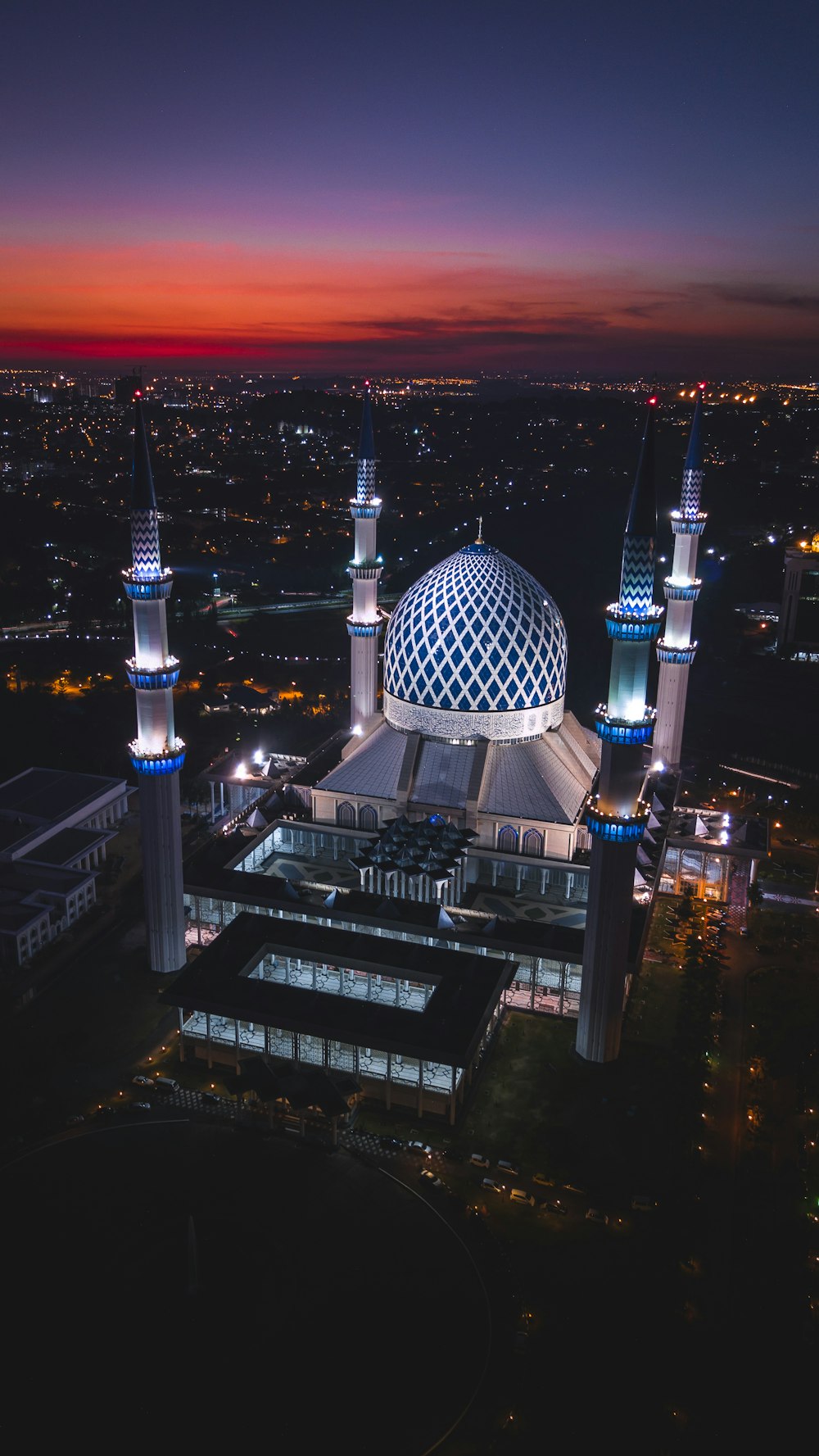 Edificio de hormigón con cúpula blanca y azul con 4 torres durante la noche