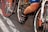 Cyclists are in close proximity, with focus on the lower body and bicycles. The image captures a busy and energetic scene likely from a race or group ride. The emphasis is on the cycling shoes, pedals, and the bicycles' frames and wheels.