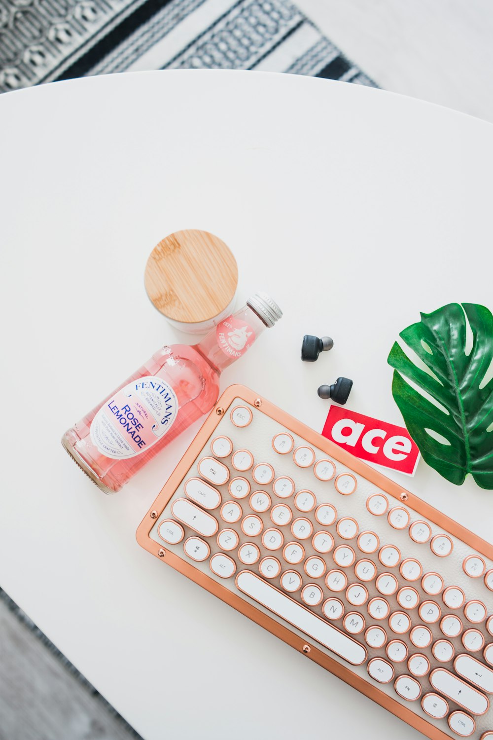 close-up photo of white and brown keyboard and pink bottle on white table