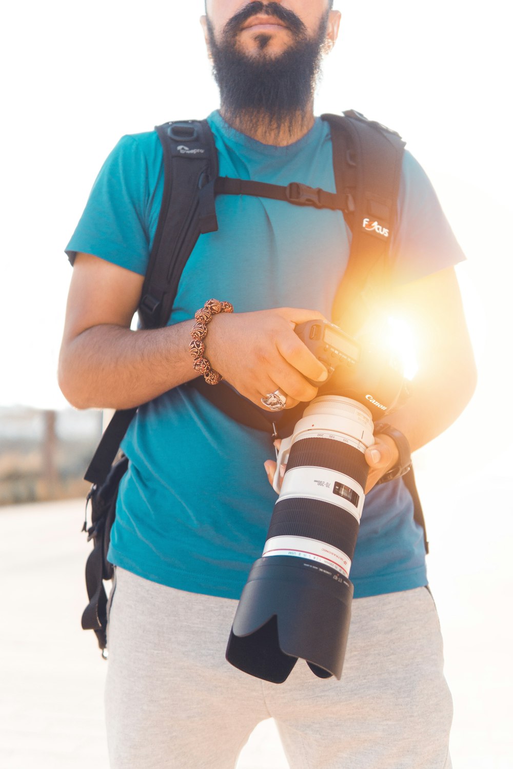 man wearing blue t-shirt holding white and black camera with lens