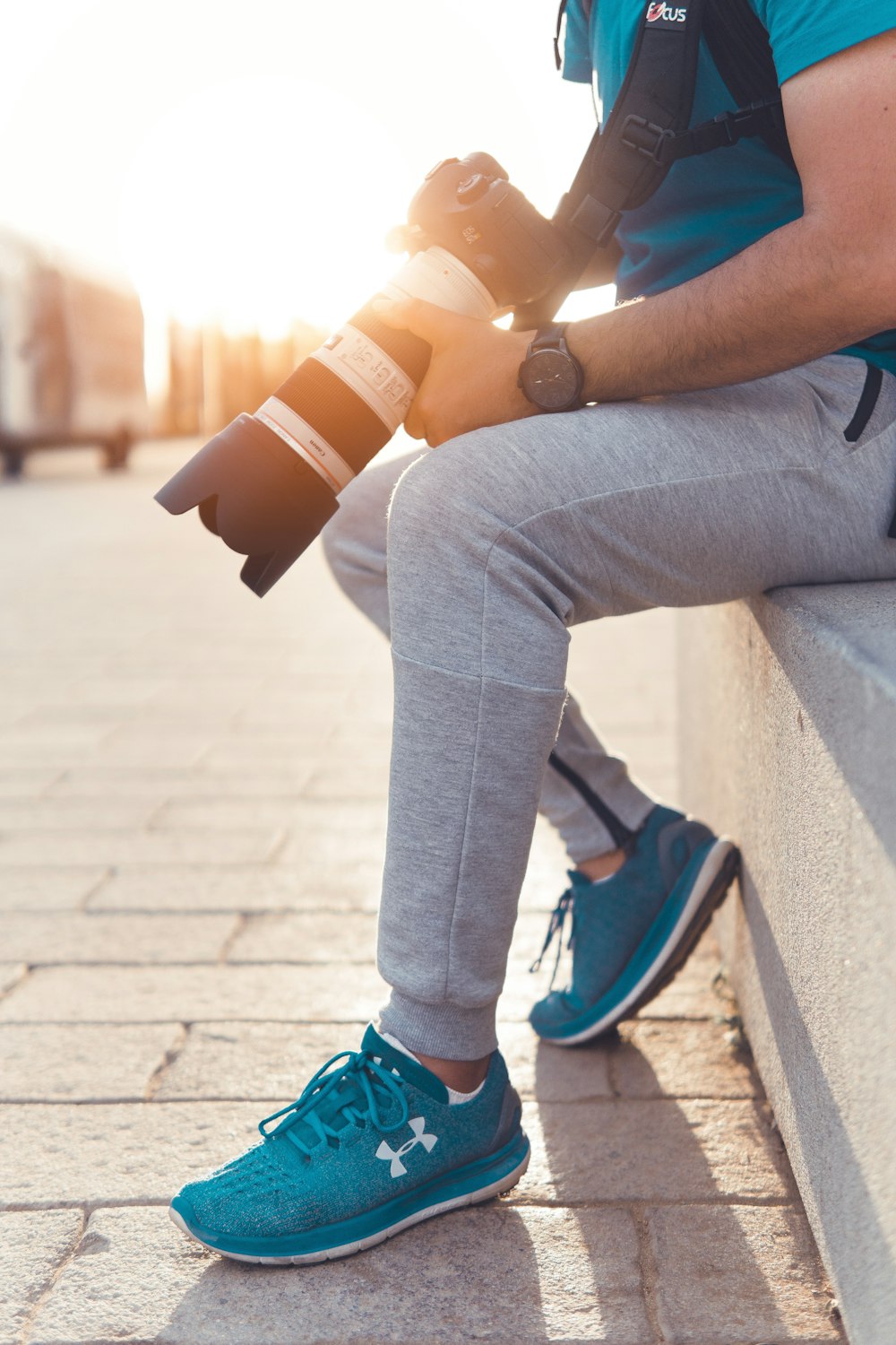 man sitting on concrete bridge holding camera