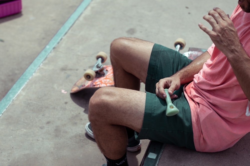 man sitting on brown wooden chair beside red skateboard