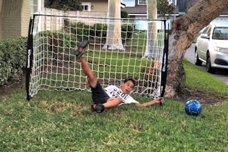 A young football player practicing dribbling on a grassy field.