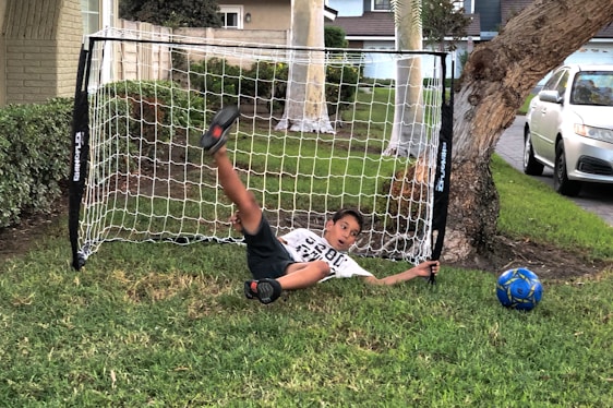 A young football player practicing dribbling on a grassy field.