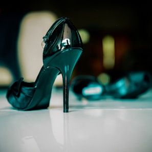 Artistic photo of black pointed-toe pumps with a glossy finish, highlighted by soft natural light.