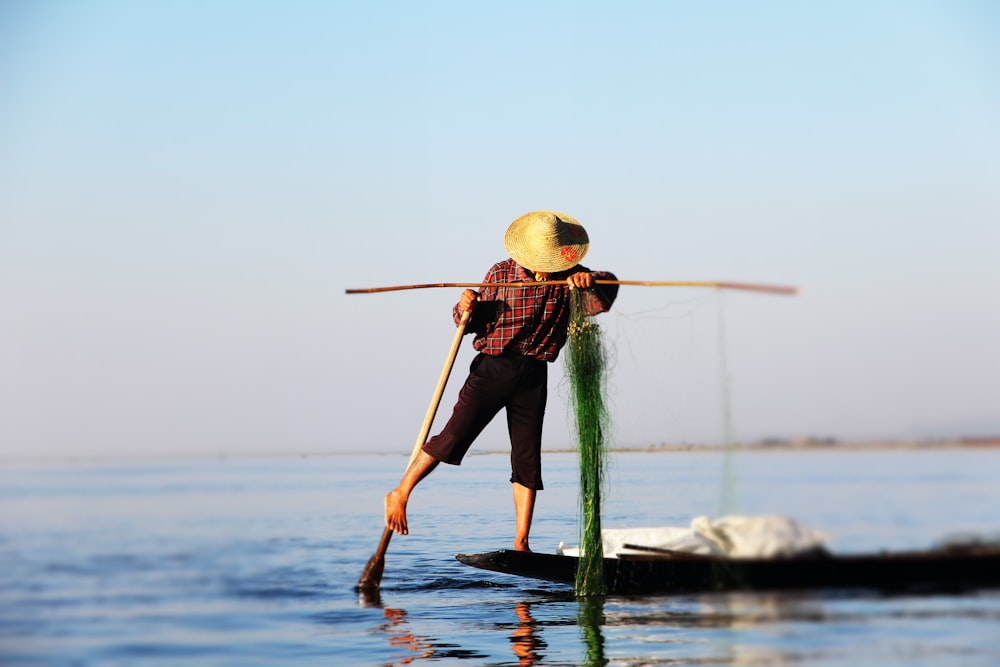 homem no barco segurando vara