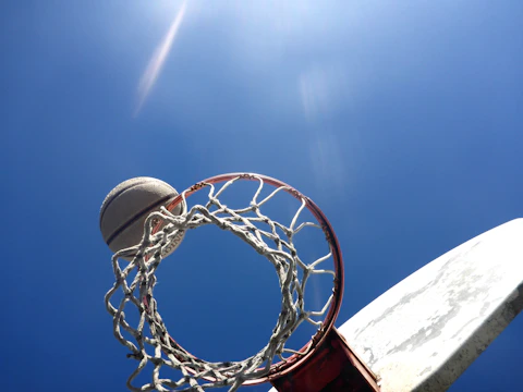 Close-up of a basketball spinning on a player's finger under bright sunlight.