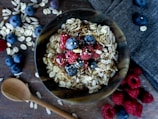 A bowl of oatmeal topped with berries and honey.