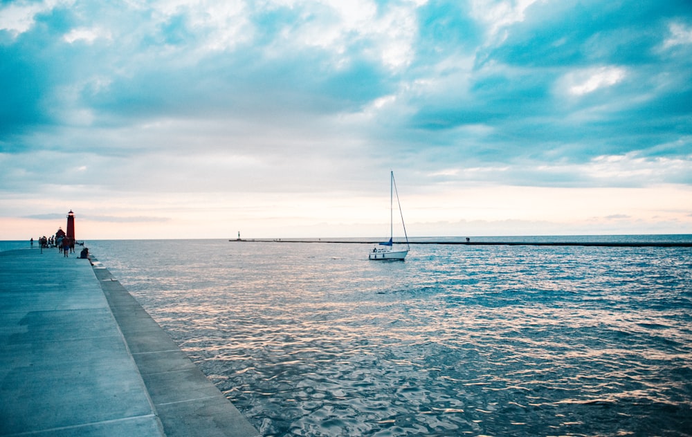 a sailboat is in the water near a pier