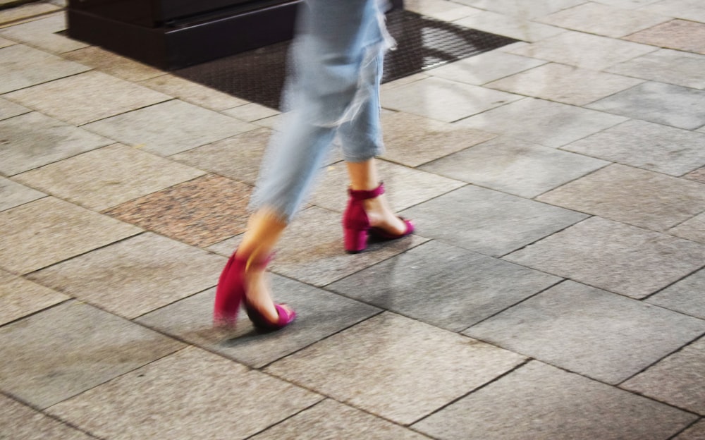 walking woman wearing blue denim jeans and pair of pink sandals