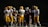 A group of American football players from two different teams, wearing distinct uniforms of yellow and maroon, gather together on a field. The scene is set at night with the players' helmets and gear clearly visible, suggesting a game or practice session. Trees are visible in the background under the night sky.