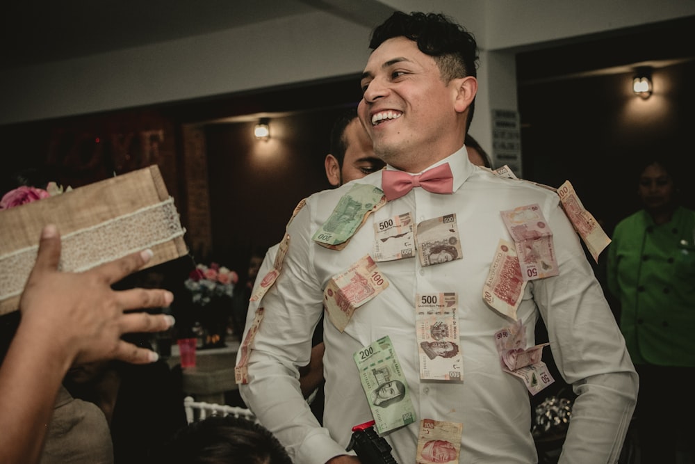 man wearing white formal suit with banknotes hanging