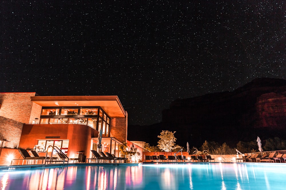 Edifício de concreto marrom e branco ao lado da piscina durante a noite