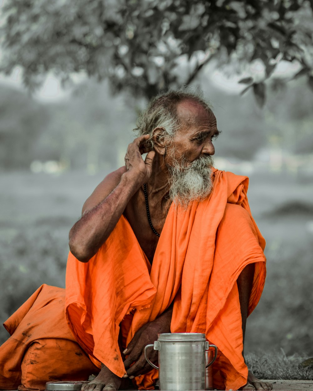 selective color photography of man sitting on ground near container