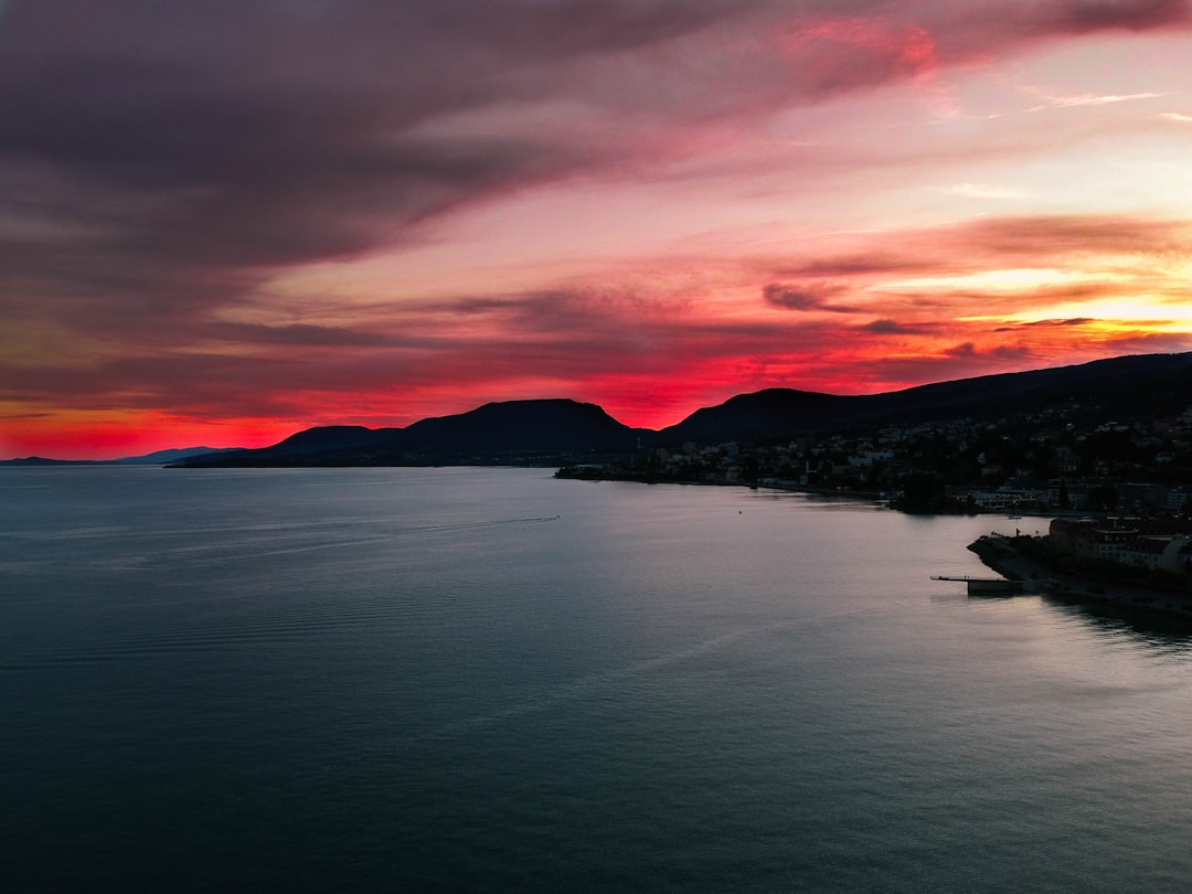 body of water near mountain during sunset