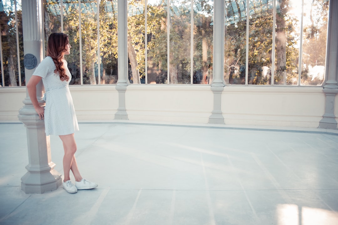 woman leaning on white concrete pillar