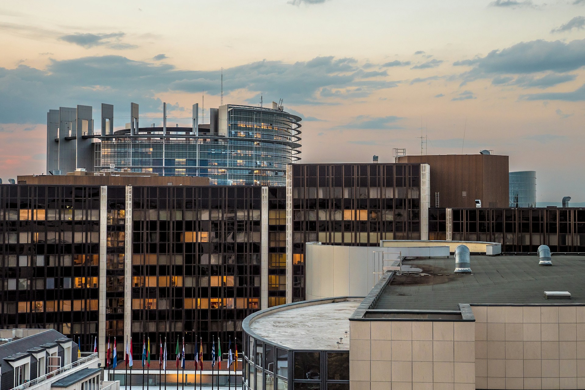 A modern news carousel card showing a cityscape at sunset with a subtle overlay and rounded corners.